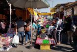 Puestos de tianguis con productos en el piso y gente comprando
