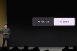 Aquí vemos una presentación con un individuo en un escenario y una pantalla grande detrás de él que muestra un símbolo de relámpago seguido de "GPT-3.5" y un diamante con "GPT-4", lo que indica una discusión sobre la transición o las diferencias entre dos versiones de modelos de lenguaje generativos de OpenAI, presumiblemente en un contexto tecnológico o de conferencia.