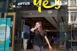 Mujer habla por telefono frente a Optus shop. 