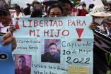 Mujder de EL Salvador con cartel que exige la liberación de su hijo.