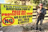Persona en el rancho de Aribabi con una pancarta en contra del tren.