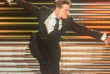 Luis Miguel con traje negro y corbata bailando en concierto