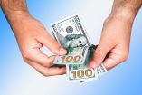 Manos sostienen billetes de 100 dólares.