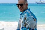 Daddy Yankee sonriendo con lentes; playa atrás