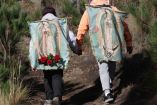 Personas caminando tomadas de la mano con imagen de Virgen de Guadalupe en espalda