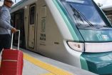 Turista con maletas subiendo al Tren Maya