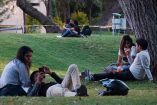 Tres parejas jóvenes sentadas en el pasto previo al día de San Valentín