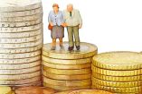 Una pareja de personas de la tercera edad están paradas sobre monedas