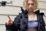 Hunter Schafer con chamarra negra y blusa morada; dron al lado