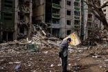 En ucrania Hombre parado frente a bloque de edificios destruidos por bombardeo ruso.