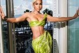 Kelly Rowland con vestido verde posando en ventana
