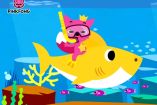  Un colorido dibujo animado de Pinkfong montando un tiburón amarillo bajo el mar, con peces y corales alrededor. El logotipo de Pinkfong aparece en la esquina superior izquierda.