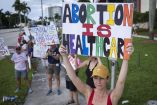 La gente sostiene carteles durante una manifestación a favor del derecho al aborto en el segundo aniversario del fallo de la Corte Suprema para revocar Roe v. Wade, en West Palm Beach, Florida.