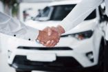 Dos manos se estrechan para cerrar la compra de un auto.