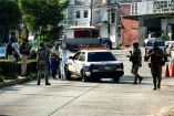 Militares parados en la calle junto a un taxi blanco con azul en Acapulco