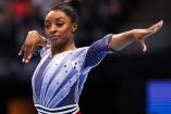 Simone Biles extendiendo el brazo izquierdo.
