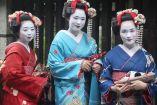 Geishas con traje y muro de madera atrás