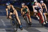Rosa María Tapia (cen) en bicicleta entre dos triatletas.