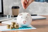 Mano coloca una moneda en alcancía.