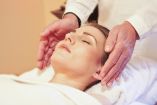 Mujer acostada con manos al lado haciendo reiki