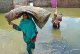 Mujeres cargan tapetes en medio de una inundación en Pakistán