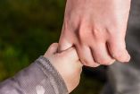 Mano de un adulto sujetando la de un niño