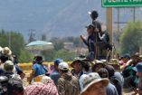Manifestantes campesinos e indígenas bloquean una carretera en Bolivia, sentados y portando herramientas de trabajo, mientras exigen la libertad de Evo Morales y protestan contra el gobierno de Luis Arce.