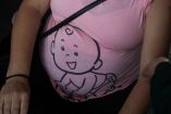 Mujer embarazada usa una playera rosa con el dibujo de un bebé