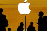 Siluetas de personas frente al logotipo de Apple iluminado en un fondo dorado, representando la relevancia de la empresa en el ámbito tecnológico y su impacto en la vida cotidiana.