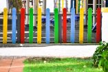 Entrada de un Jardín de Niños con una cerca pintada de colores