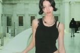 Lucy Markovic con top negro y museo atrás
