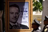 Retrato enmarcado de Pedro Infante acompañado de una frase conmemorativa y flores, observado por oficiales uniformados durante un homenaje póstumo en México