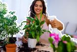 Mujer rociando y cuidando plantas mientras les habla, ilustrando la creencia de que hablarle a las plantas favorece su crecimiento.