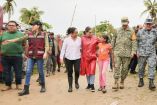 La gobernadora Evelyn Salgado camina junto a una niña y elementos del Ejército y Marina en una comunidad afectada de la Costa Chica tras el paso del huracán Erick, acompañada también por funcionarios estatales y brigadistas que participan en las labores de ayuda humanitaria y evaluación de daños.