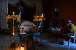 En Santa María de Jesús, Guatemala, familiares asisten al velorio de Carlos Cuy, quien murió tras la serie de sismos ocurridos el 9 de julio de 2025. La imagen muestra una habitación iluminada por velas, con un ataúd rodeado de flores y mujeres indígenas en luto, reflejando el duelo y la precariedad tras la emergencia.