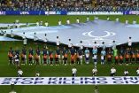 Niños refugiados y jugadores posaron frente a la pancarta de la UEFA que llama a detener la violencia contra civiles y menores (Facebook/UEFA)
