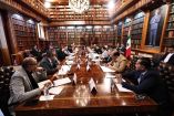 Imagen de una reunión oficial en la biblioteca de la Secretaría de Gobernación entre consejeros del INE y funcionarios federales, sentados en torno a una mesa larga de madera, con estanterías de libros y una gran pintura al fondo. Se discuten temas clave sobre la reforma electoral en México.