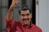 El presidente de Venezuela, Nicolás Maduro, sonríe y levanta el puño en señal de determinación durante un acto oficial, vestido con camisa roja, en el contexto de su reciente advertencia sobre el despliegue militar de Estados Unidos en el Caribe y las tensiones geopolíticas en la región.