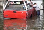 Un señor parado junto a una camioneta en calles inundadas de Iztapalapa