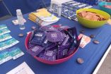 Mesa informativa de Madrid Salud con preservativos, folletos educativos y pruebas rápidas de VIH como parte de una jornada de sensibilización sobre salud sexual en Madrid.