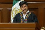 El ministro presidente de la Suprema Corte de Justicia de la Nación, Hugo Aguilar Ortiz, rinde su Primer Informe de Labores en el Pleno de la SCJN, vestido con toga negra decorada con bordados de colores y con el escudo nacional al fondo