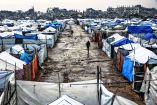 Men walk along a muddy alley at a makeshift camp sheltering displaced Palestinians after heavy rains in the Zeitoun neighbourhood of Gaza City on December 11, 2025. The United States, alongside Qatar and Egypt, secured a truce in Gaza that came into effect on October 10 and has mostly halted two years of war between Israel and Palestinian militant group Hamas. (Photo by Omar AL-QATTAA / AFP)