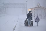 Una mujer y un niño se dirigen con su equipaje a la estación de tren de Are mientras la tormenta Johannes avanza sobre el norte de Suecia provocando la cancelación de vuelos.