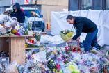 Una persona de luto deposita un ramo de flores en un monumento improvisado cerca del bar Constellation