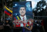 Una mujer muestra una pintura que representa al derrocado presidente venezolano, Nicolás Maduro