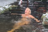 Mujer sumergiéndose en agua helada durante festival Vodohreshya en Kyiv Urania