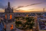 Panorámica aérea del centro histórico de Mérida, Yucatán, al atardecer, con la catedral y edificios coloniales iluminados, mostrando el entorno urbano y la actividad de la ciudad.