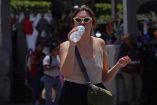 Una mujer bebé agua para mitigar el calor en el Zócalo capitalino.