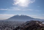 Panorámica de Monterrey vista desde un cerro en la colonia Vista Real, en San Pedro Garza García, con la zona urbana extendida y el Cerro de la Silla al fondo bajo un cielo despejado, en marzo de 2021.