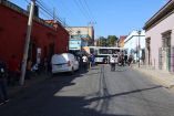 Bloqueo de calles en el Centro Histórico de la ciudad de Oaxaca por maestros de la Sección 22, con autobús detenido y peatones durante la protesta por el pago de horas-clase adeudadas.